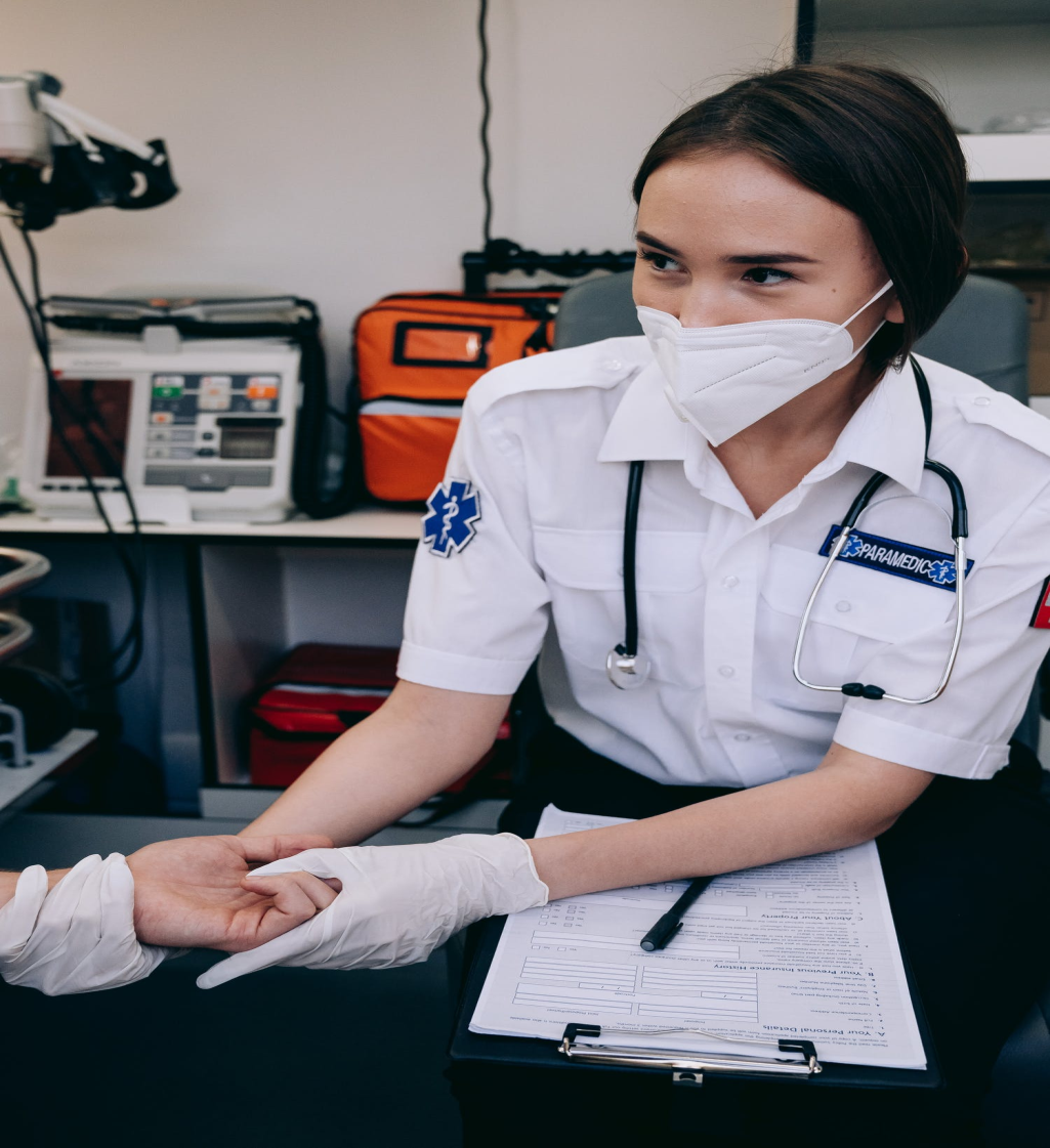 Paramedic staff wearing a mask holding patient's hand
