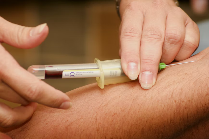 Lab phlebotomist drawing blood from a person’s arm