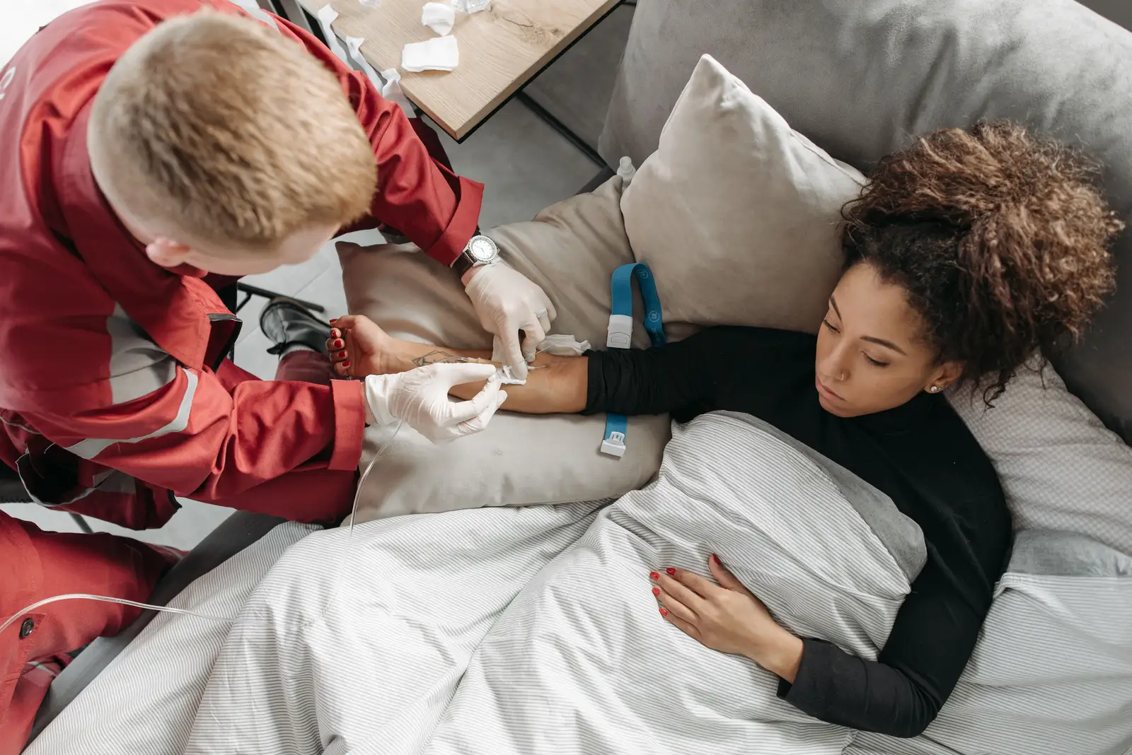 Phlebotomist drawing blood from a home health patient resting on a couch at home
